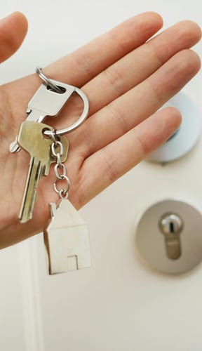 Hand holding house keys at a front door