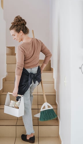 Cleaner carrying supplies up a staircase