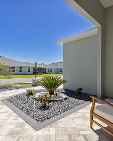 Front patio of a Florida home with outdoor seating chairs and landscaped garden under a clear blue sky